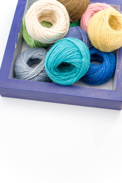 multicolored decorative yarn balls in a wooden box on a white surface - Foto, Bild