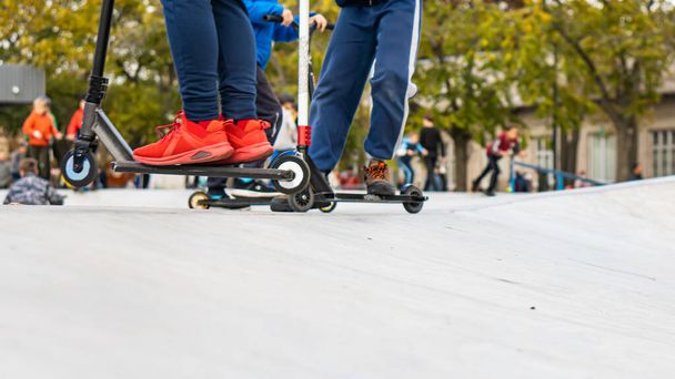 los jóvenes viajan en el campo de deportes, en scooters y patines. deportes callejeros. - Foto, Imagen