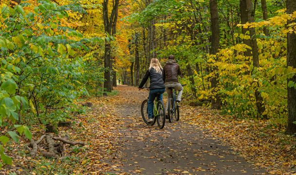 people cycling in the autumn park, riding on the tracks. - Photo, Image