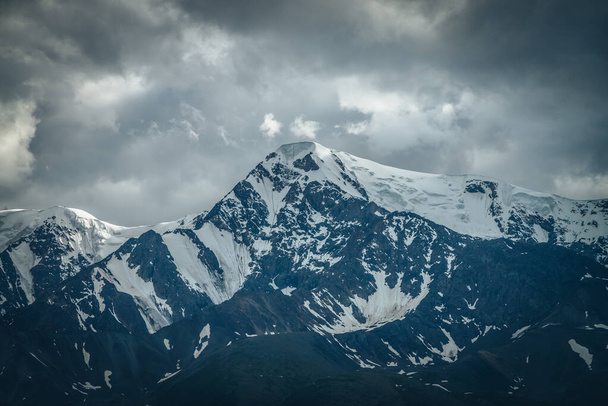 Dramatic mountains landscape with big snowy mountain ridge under cloudy sky. Dark atmospheric highland scenery with high mountain range in overcast weather. Awesome big mountains under gray clouds. - Fotoğraf, Görsel