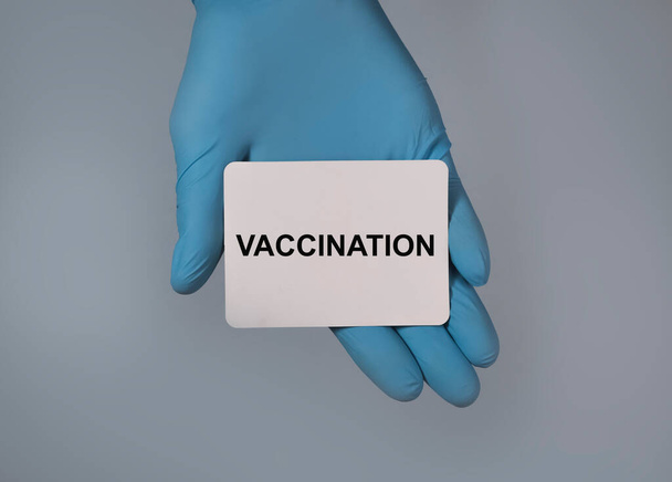 Vaccination word on paper in hand in glove - Foto, afbeelding