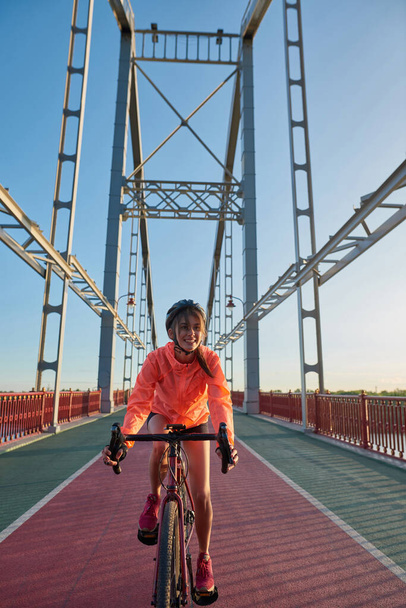 Smiling millennial girl ride bike on city bridge - Fotografie, Obrázek