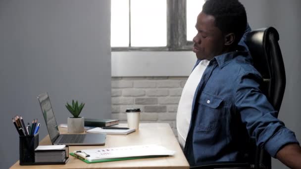 Moe Afro-Amerikaanse man strekt gespannen spieren na hard werken op laptop - Video