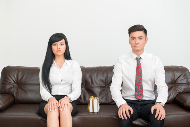 Business couple sitting on sofa in office with present - Photo, image