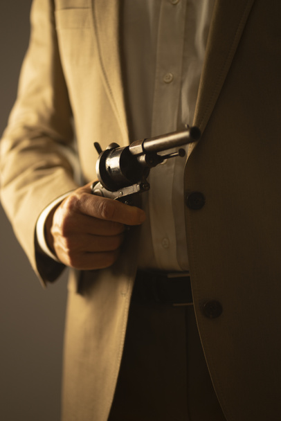 Male detective spy killer holding pistol gun in dramatic novel book cover design color photo. - Foto, afbeelding