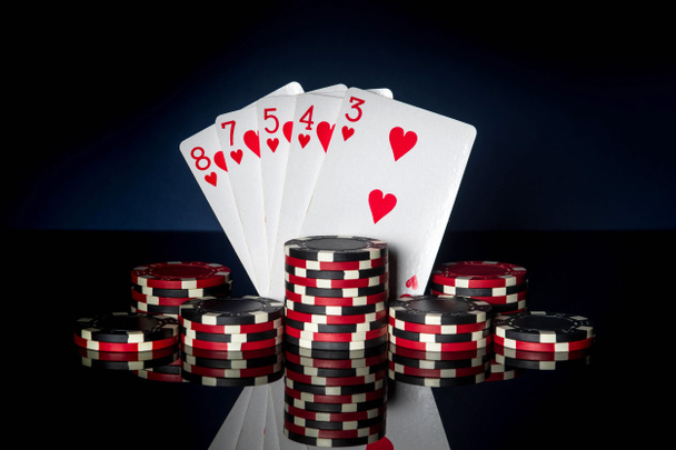 Игра в покер с комбинацией стрит-флеш. Чипсы и карты на черном столе. Успех и победа - Фото, изображение