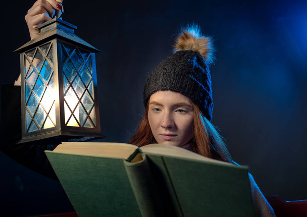 Retrato de menina bonita cabelo vermelho segurando livro velho e lanterna à noite na leitura  - Foto, Imagem
