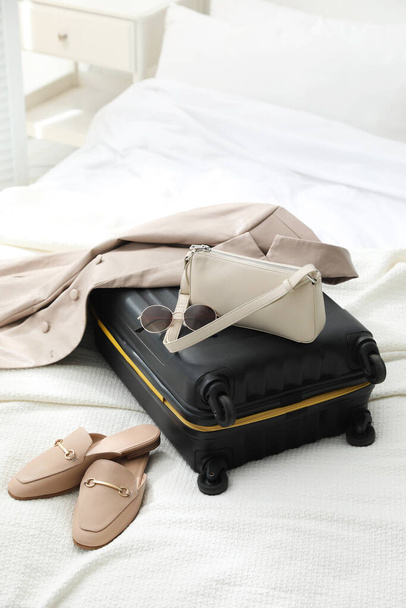 Чемодан упакован для поездки, обувь, пиджак и модные аксессуары на кровати - Фото, изображение