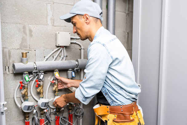 Encanador masculino verifica tubos para abastecimento central de água quente e fria do apartamento - Foto, Imagem
