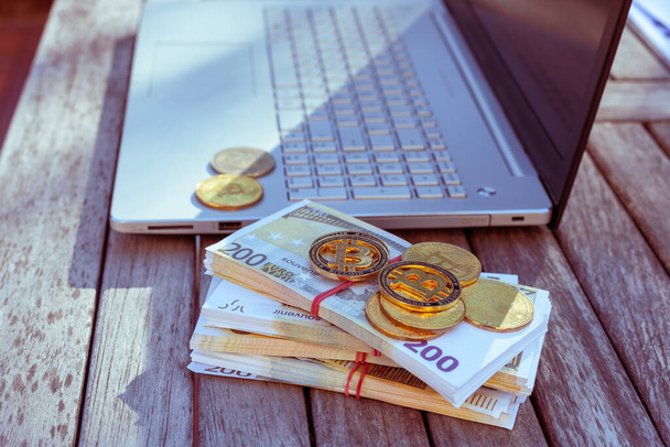 Ci sono soldi bitcoin e un computer portatile sul tavolo. Monete Bitcoin si trovano su carta euro. - Foto, immagini