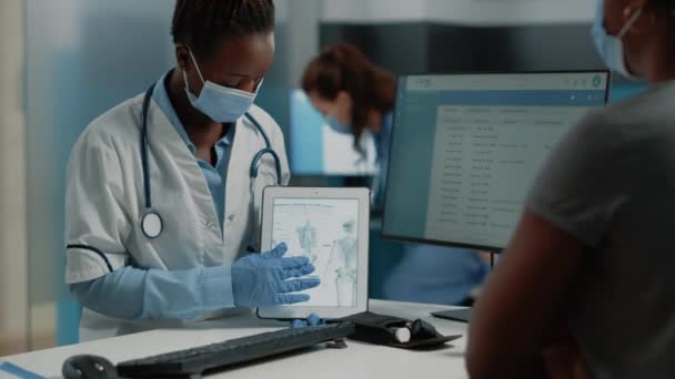 Lääkintämies näyttää tabletin ihmisen luurangon kanssa potilaalle - Materiaali, video