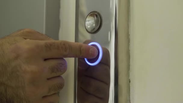 El dedo del hombre alcanza y presiona el botón del ascensor que se ilumina. HDR. Cierre de botones metálicos de un ascensor público. - Imágenes, Vídeo
