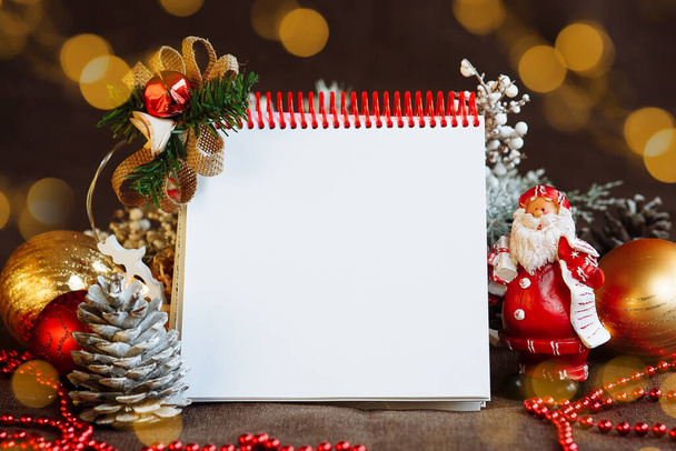 Notepad with a space for text among Christmas decorations highlights and santa Claus mock up - Fotoğraf, Görsel