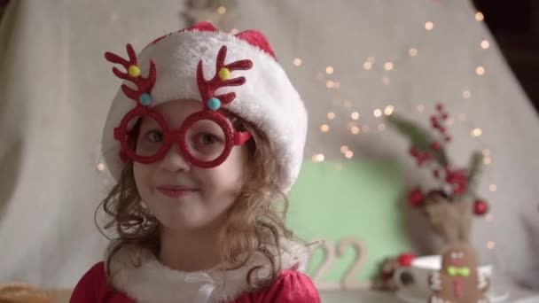 Маленькая размытая девочка в шляпе Санты наслаждается Рождеством. Рождественские подарки Концепция детства.  - Кадры, видео