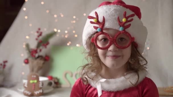 Wazig klein meisje met kerstmuts geniet van de kersttijd. Kerstmis presenteert vakantie kindertijd concept.  - Video