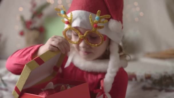 Verschwommenes kleines Mädchen mit Weihnachtsmütze genießt die Weihnachtszeit. Weihnachten präsentiert Kinderferienkonzept.  - Filmmaterial, Video