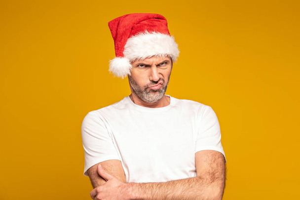 Portrait of disappointed bearded man wearing santa claus hat, looking at the camera and making faces. Xmas time. Christmas sales concept. A lot of copy space - Фото, зображення