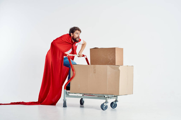 Veselý muž v červeném plášti transport v krabici světlo pozadí - Fotografie, Obrázek