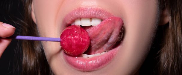 Licking tongue lips. Sexy woman mouth with pink lips holding lollipop, beauty closeup. Sexy girl suck lick lollipop. Beauty glamour concept, close-up. - Photo, Image