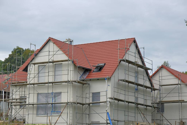 Home construction.Scaffolding close-up. New house with roof in scaffolding.Building materials and the process of building a new house. - 写真・画像