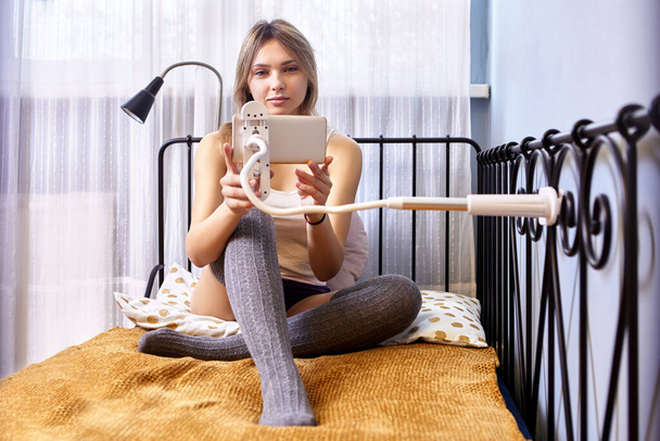 Smartphone is fixed by phone holder to bed by woman. - Foto, immagini