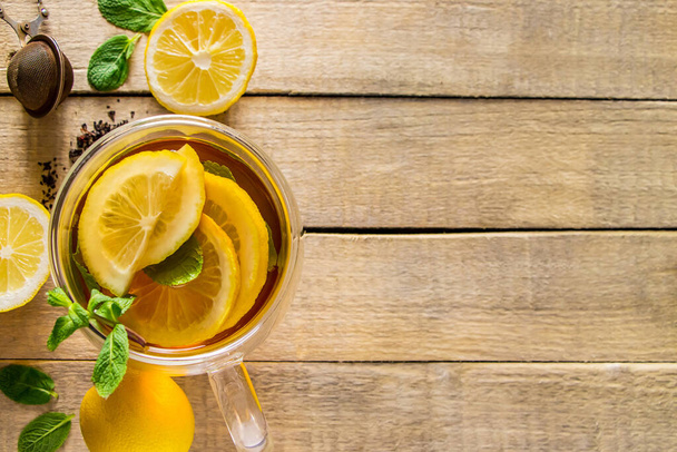 Чай с лимоном и мятой в прозрачной чашке. Альтернативная медицина. Горячий напиток для отдыха. - Фото, изображение