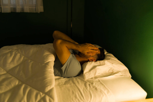Nem tudok aludni. Aggódó fiatalember eltakarja az arcát és álmatlanságban szenved.  - Fotó, kép
