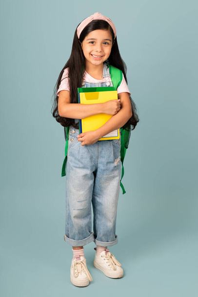J'adore aller à l'école. Petite fille mignonne regardant la caméra tout en portant un sac à dos et portant des livres - Photo, image