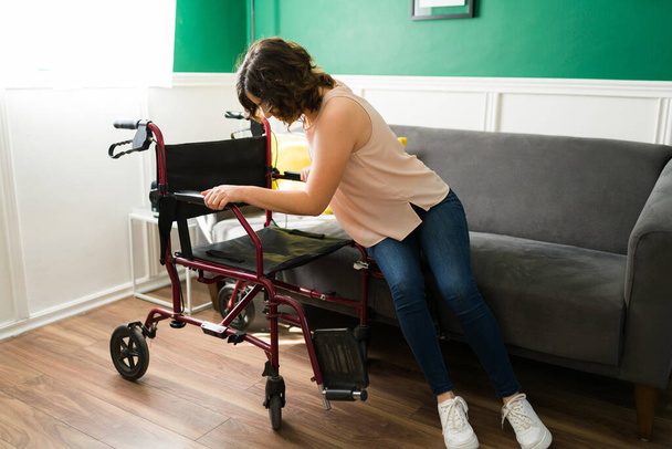Junger Mann mit Behinderung bewegt sich von der Couch in ihren Rollstuhl. Behinderte zu Hause - Foto, Bild
