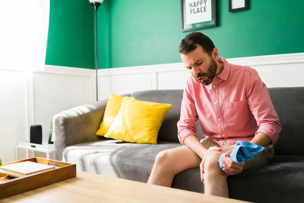 Hombre en edad de 30 años con un músculo tenso y una lesión en la rodilla usando una compresa fría en la pierna - Foto, imagen