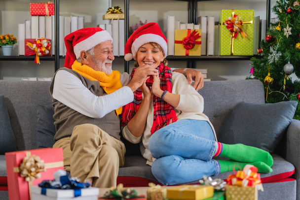 caucasian senior couple sitting together in living room at home and feeling happy with Christmas gift and present during Christmas and new year celebration festival - 写真・画像