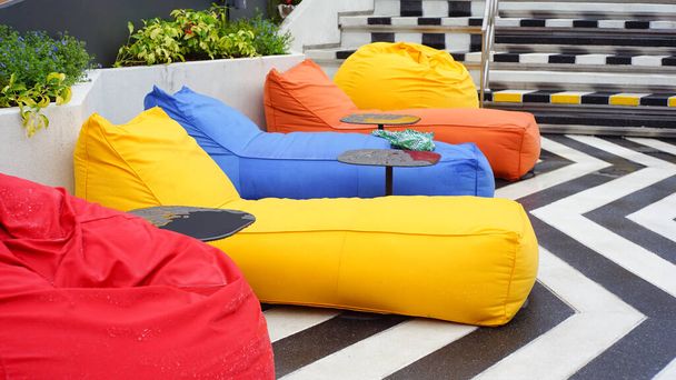 multicolor bean bags and black table side swimming pool. - Photo, Image