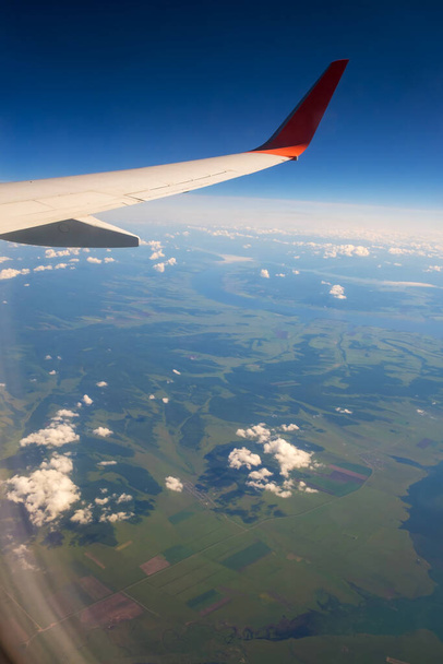 Klasszikus kép a repülőgép ablakán át a szárnyra. Repüléskilátás Oroszország felett - Fotó, kép