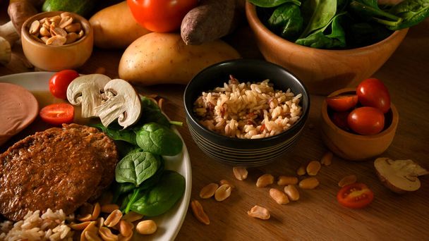 Heathy pasto vegan e cibo a base vegetale concetto, carne vegan con riso integrale, noci e verdure su un tavolo di legno. - Foto, immagini