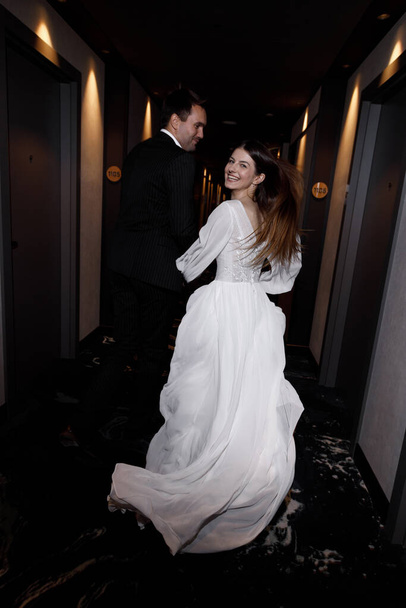 Wedding photo shoot with a lobby and restaurant, on a dark background. Beautiful young bride and groom in a stylish hotel. - Foto, Imagen