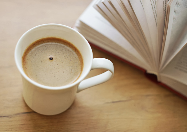 Frisch gebrühte Kaffeetasse gegen Buch. - Foto, Bild