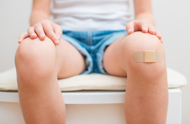 Детское колено с клейкой повязкой. - Фото, изображение