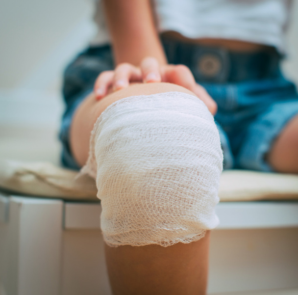 Child knee with adhesive and gauze bandage. - Photo, image