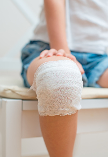 Child knee with adhesive and gauze bandage. - Фото, зображення