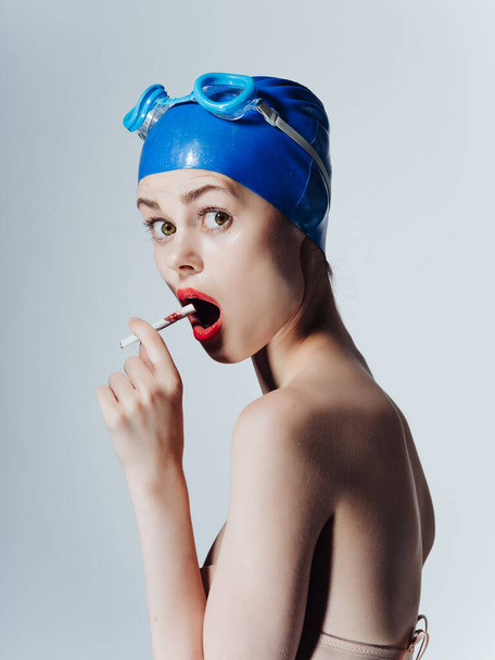 mulher atlética em óculos de natação fuma um cigarro em fundo isolado. Foto de alta qualidade - Foto, Imagem