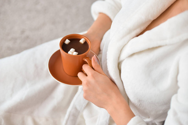 Bella giovane donna con tazza di bevanda calda al cacao e marshmallow a casa - Foto, immagini