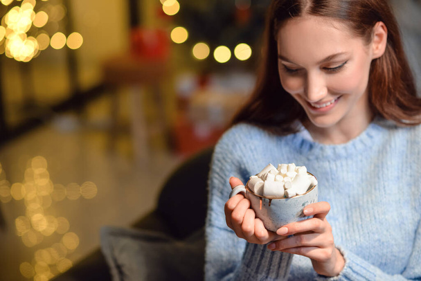 Kaunis nuori nainen kupin kuumaa kaakaota juoda kotona jouluaattona - Valokuva, kuva