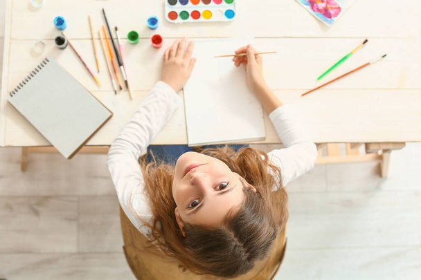 Милая маленькая девочка рисует дома, вид сверху - Фото, изображение