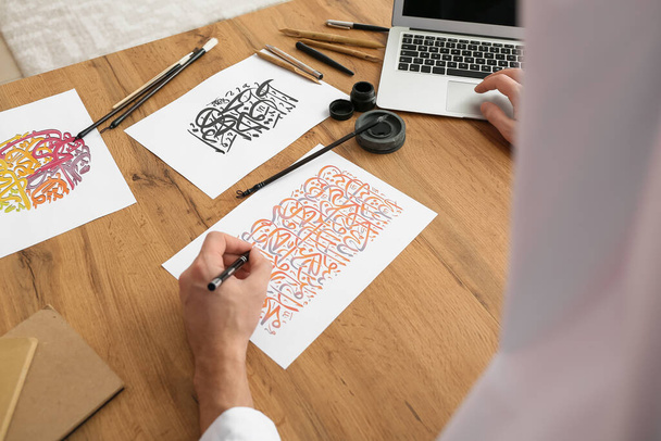 Mężczyzna arabski kaligrafik pracujący w biurze - Zdjęcie, obraz