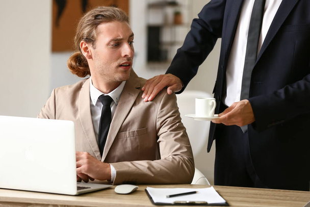 Man seducing his male colleague in office. Concept of harassment - Photo, Image