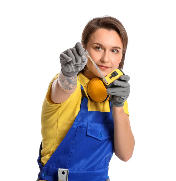 Vrouwelijke bouwvakker met meetlint op witte achtergrond - Foto, afbeelding