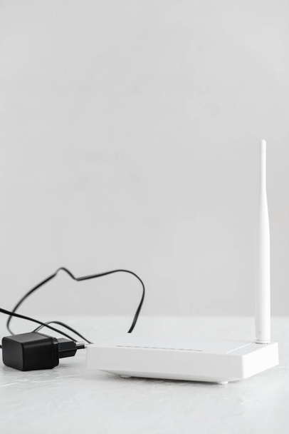 Modern wi-fi router on table near white wall - Фото, изображение