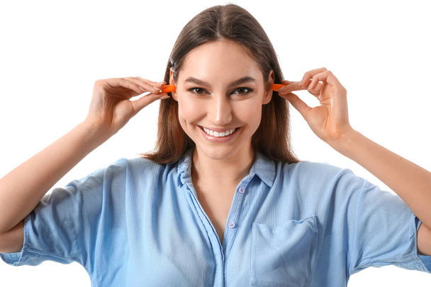 Mladá žena vkládání špunty do uší na bílém pozadí - Fotografie, Obrázek