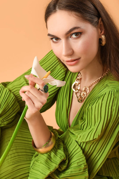 mooie jonge vrouw met calla bloem op kleur achtergrond - Foto, afbeelding