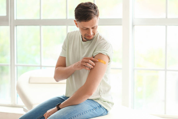 Man met medische pleister op zijn arm in de kliniek - Foto, afbeelding